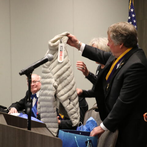 International Director Allen Snider unwraps his gift of an embroidered jacket at the Iowa Lions State Convention.